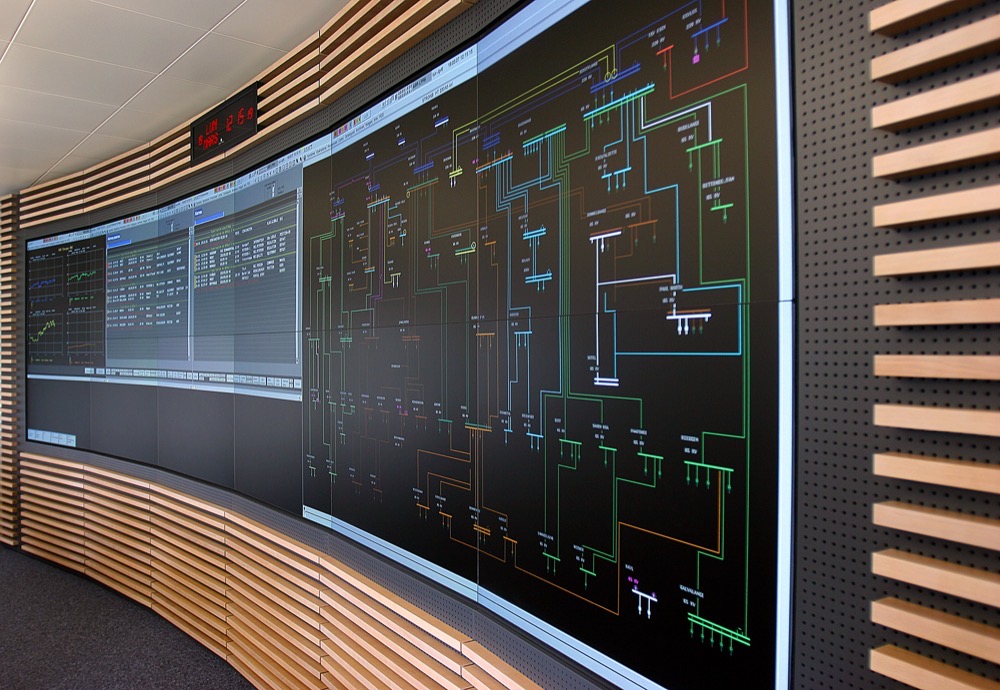 A transmission network schematic lit up across a grid control room video wall